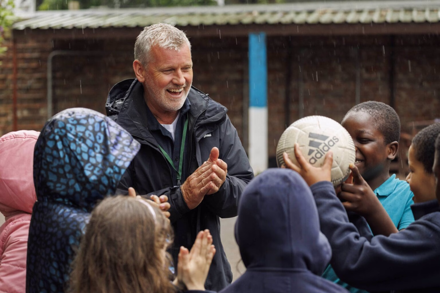 Eric black stood with a group of kids passing a ball by hand